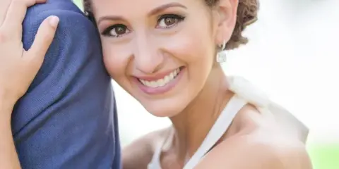 Bride in a white dress smiling while embracing a groom in a blue suit