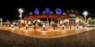 Wide-angle night photograph of a building exterior with illuminated 'ABQ' signage and a cobblestone plaza.