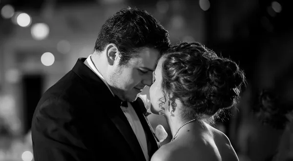 A black and white photograph of a bride and groom sharing a first dance at a wedding reception.