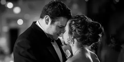 A black and white photograph of a bride and groom sharing a first dance at a wedding reception.