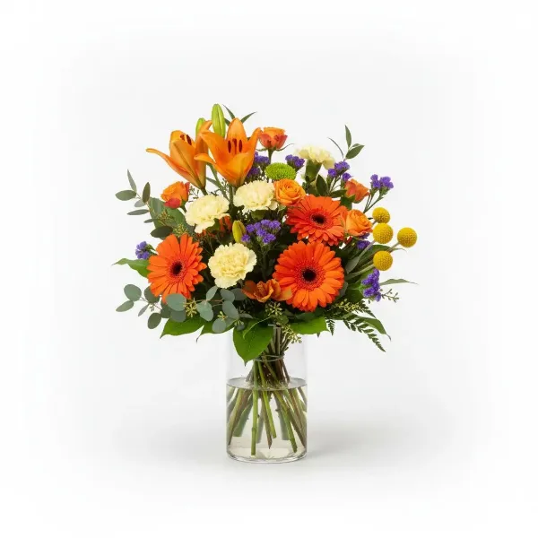 A vibrant floral arrangement featuring orange lilies, gerbera daisies, and carnations in a clear glass vase.