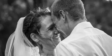 Black and white photo of a bride and groom touching foreheads and smiling.
