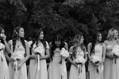 A black and white photograph of a line of bridesmaids holding bouquets.