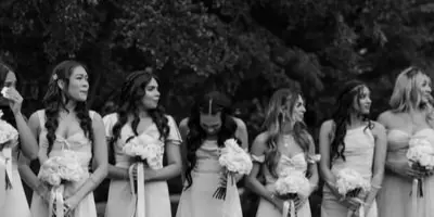A black and white photograph of a line of bridesmaids holding bouquets.