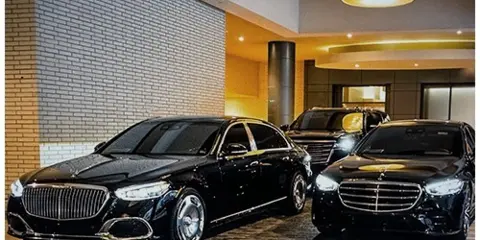 A group of black luxury sedans parked in a modern lobby or garage.