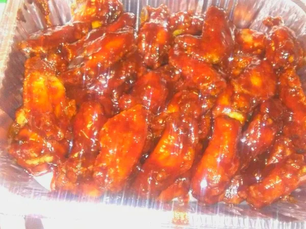 A large aluminum tray filled with sauced chicken wings