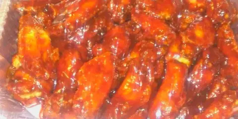 A large aluminum tray filled with sauced chicken wings