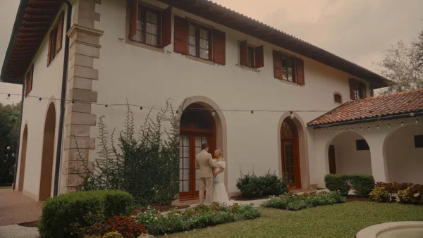 Bride and groom standing and reading their wedding vows in front of a white stucco venue building.