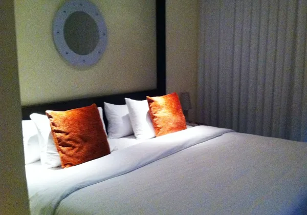 A bedroom with a large bed, white linens, and orange accent pillows.