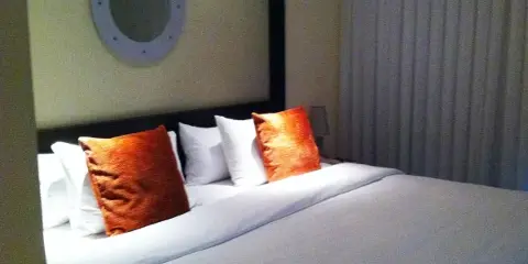 A bedroom with a large bed, white linens, and orange accent pillows.