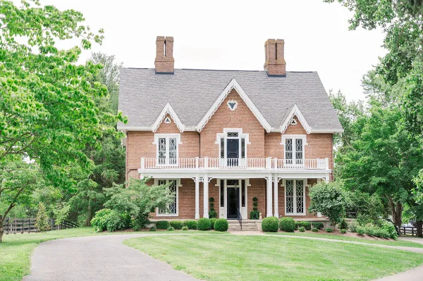 Exterior view of the historic brick Warrenwood Manor house with a white porch and manicured lawn.