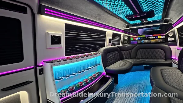 Interior of a luxury party bus with leather seating, a bar, and LED lighting.
