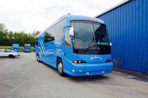 A blue Blue Grass Tours motorcoach parked in a lot.
