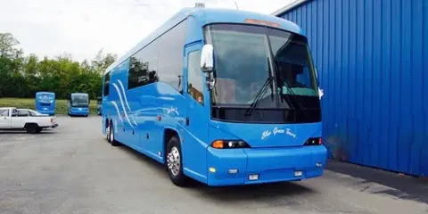 A blue Blue Grass Tours motorcoach parked in a lot.