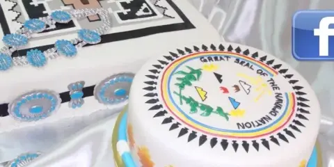 A white cake decorated with Native American geometric patterns and edible blue and silver jewelry designs.