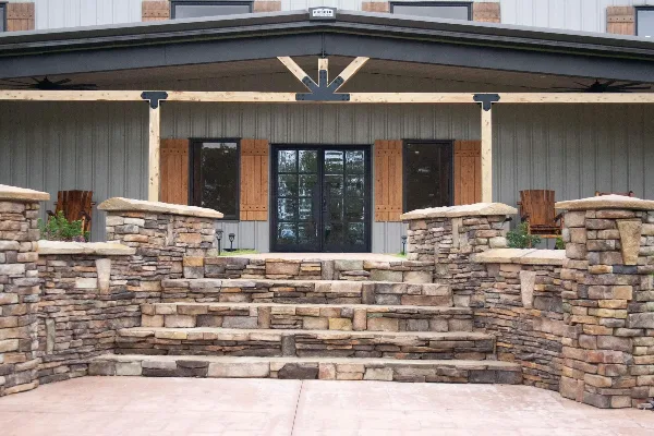 Exterior view of a modern farmhouse event venue with stone steps and a covered porch.