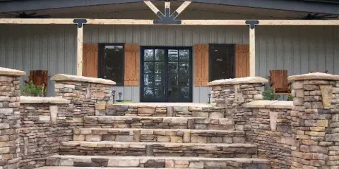 Exterior view of a modern farmhouse event venue with stone steps and a covered porch.