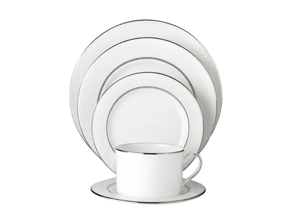 A set of white dinner plates and a matching cup with gold rims arranged on a white background.
