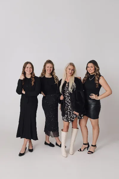 A group portrait of four women, the wedding planning team, standing together in a studio setting.
