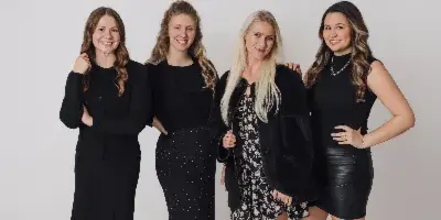 A group portrait of four women, the wedding planning team, standing together in a studio setting.