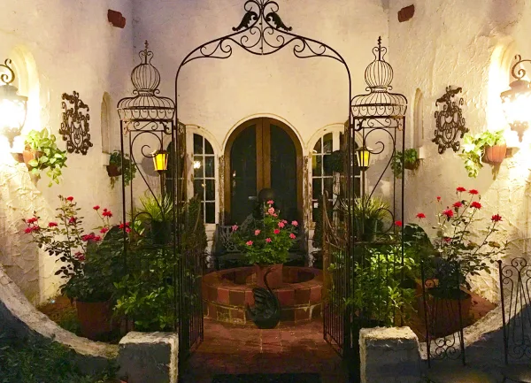 Decorated wedding courtyard with wrought iron arch, potted flowers, and seating area