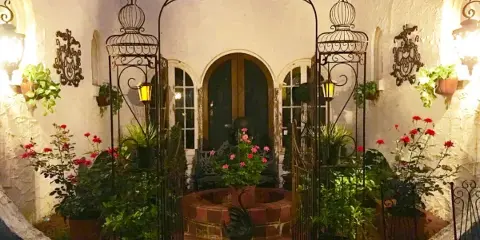 Decorated wedding courtyard with wrought iron arch, potted flowers, and seating area