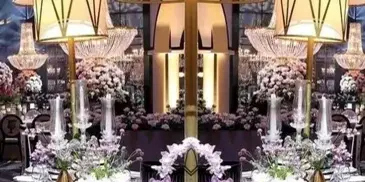 A formal event table setting featuring a large floral centerpiece, decorative lamps, and elegant place settings.
