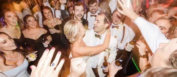 A bride and groom dancing with guests at a wedding reception.