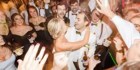 A bride and groom dancing with guests at a wedding reception.