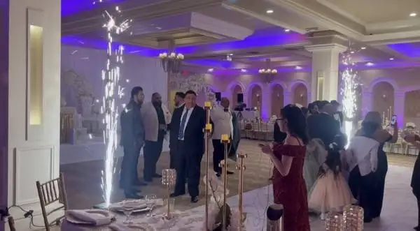 A wedding reception with guests on a dance floor and sparkler effects in a banquet hall.