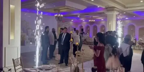 A wedding reception with guests on a dance floor and sparkler effects in a banquet hall.