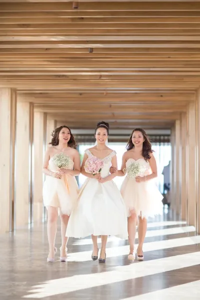 A bride and two bridesmaids walking down a hallway in a wedding venue.