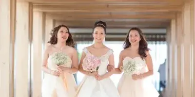 A bride and two bridesmaids walking down a hallway in a wedding venue.