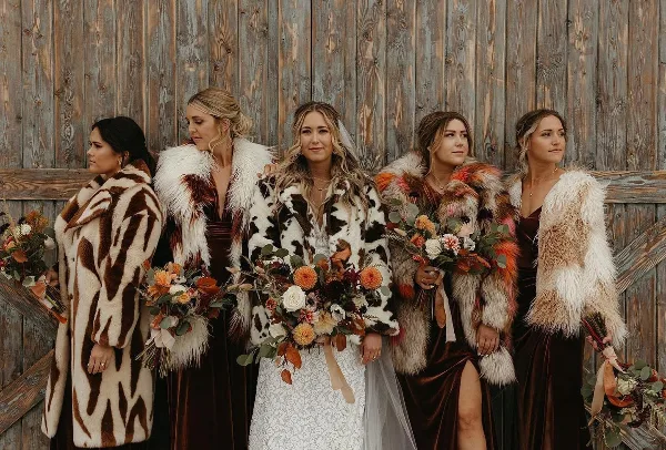 Bride and bridesmaids with styled hair and makeup standing in front of a wooden wall