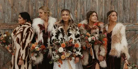 Bride and bridesmaids with styled hair and makeup standing in front of a wooden wall