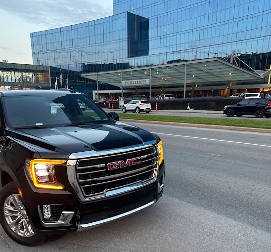 Black GMC Yukon XL Denali SUV parked outside a modern glass building