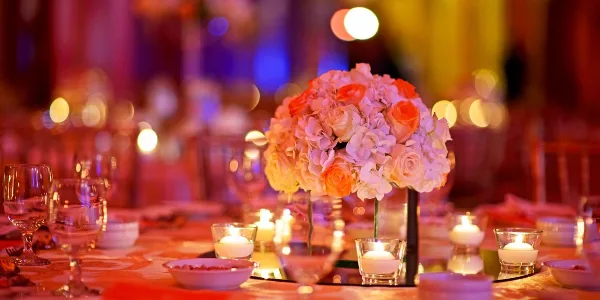 Wedding reception table with floral centerpiece, candles, and colorful event lighting