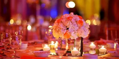 Wedding reception table with floral centerpiece, candles, and colorful event lighting