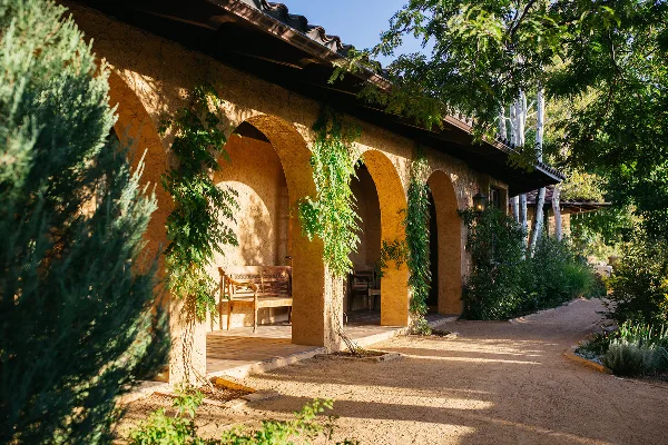 Exterior view of a Mediterranean-style estate venue featuring arched walkways, stucco walls, and lush greenery.