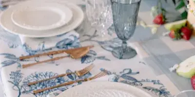 A close-up of an elegant event table setting featuring white plates, blue patterned linens, and glassware.