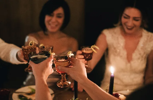 A bride and guests toasting with cocktails at a wedding reception table.
