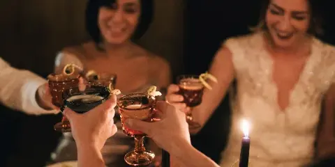 A bride and guests toasting with cocktails at a wedding reception table.