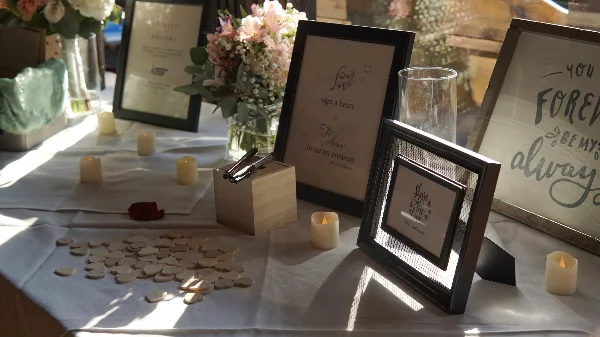A wedding guest book table decorated with floral arrangements, candles, and framed signs.