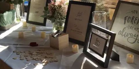 A wedding guest book table decorated with floral arrangements, candles, and framed signs.