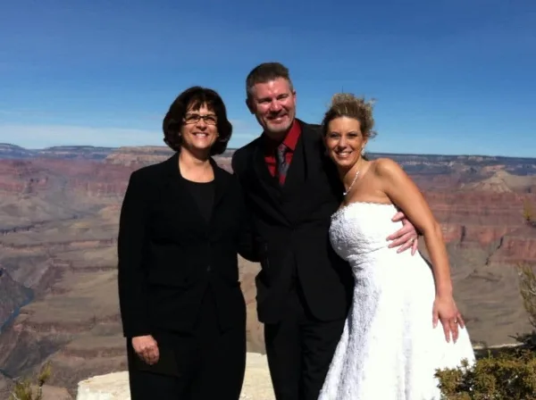 A bride and groom posing with a wedding officiant at the Grand Canyon.