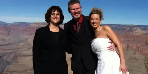 A bride and groom posing with a wedding officiant at the Grand Canyon.