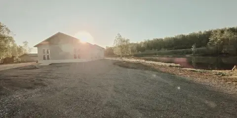 Lakefront event venue building with gravel parking area and water view at sunset