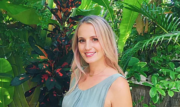 Portrait of Diana, the founder of Happily Maui'd, standing in front of tropical foliage.