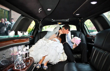Bride and groom kissing inside a luxury limousine