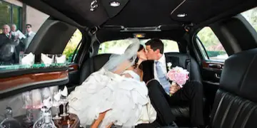 Bride and groom kissing inside a luxury limousine